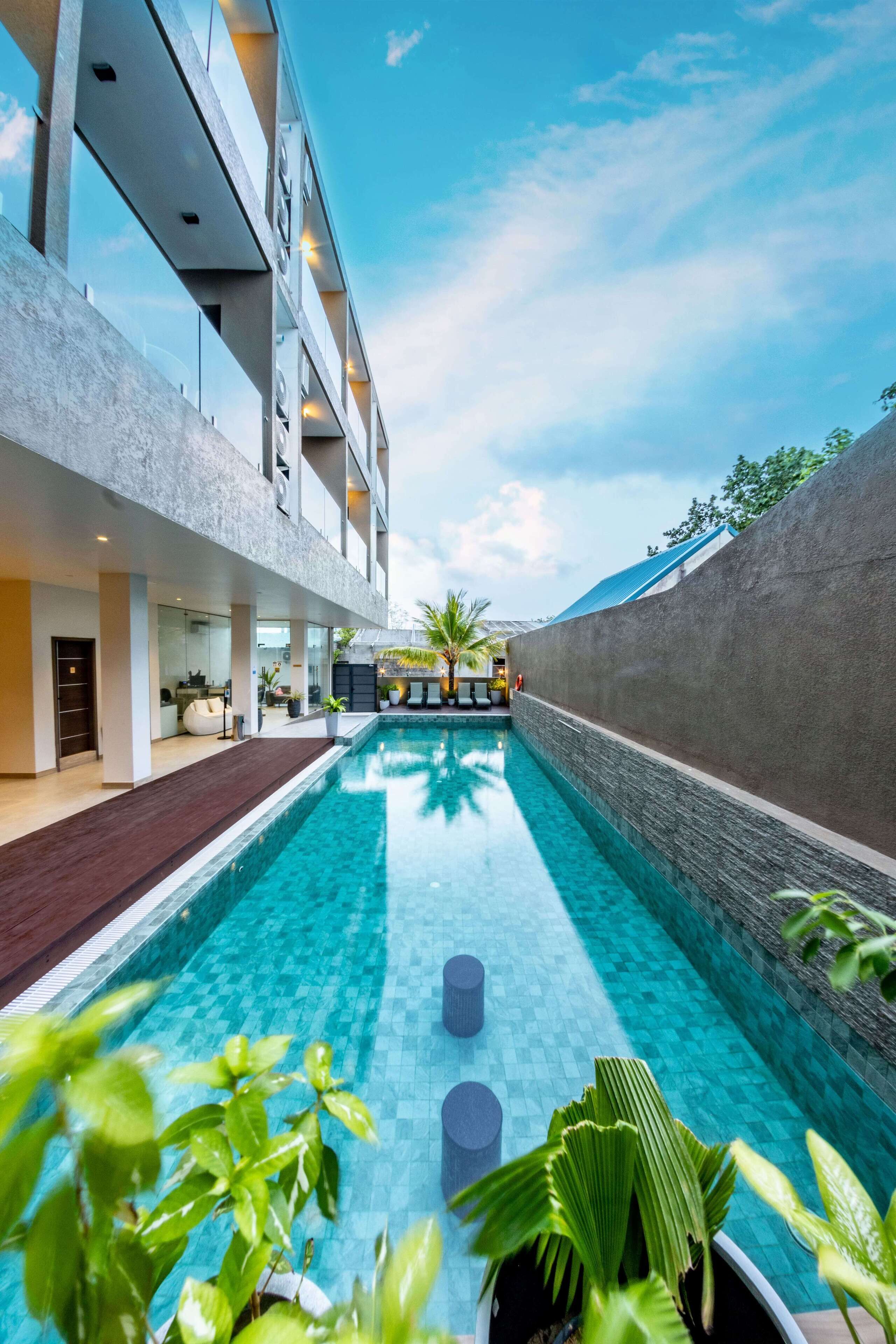 A modern hotel with a central swimming pool, a covered outdoor area, and a view of the sky.