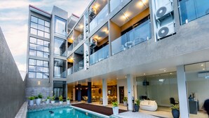 Een modern gebouw met een zwembad, balkons en grote ramen.