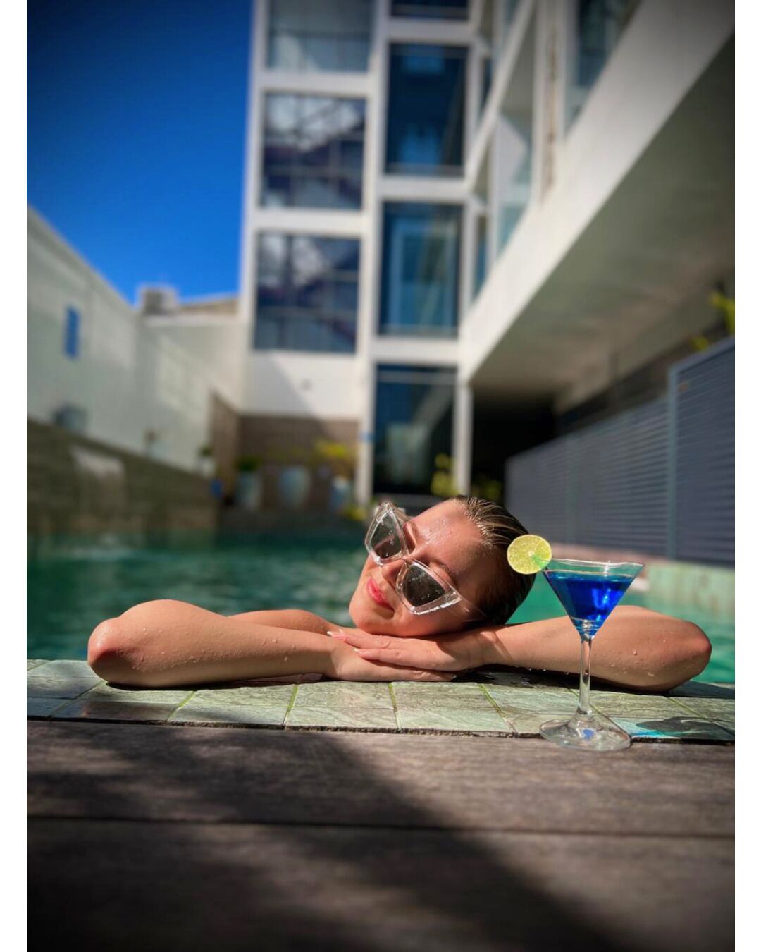 A person relaxing by a pool with a drink.