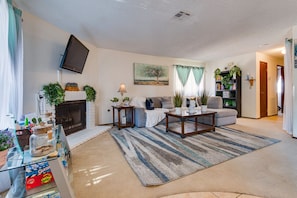 A living room with a fireplace, sofa, coffee table, and various plants. - 🌈Tranquil condo with cozy king beds🌈decaf/ regular coffee✨work from🏡✨fast wifi✨ (Las Vegas)