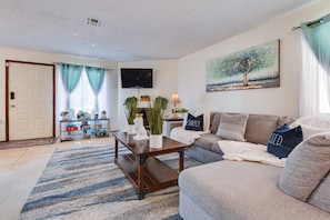 A living room with a sofa, a coffee table, a TV, and a painting on the wall. - 🌈Tranquil condo with cozy king beds🌈decaf/ regular coffee✨work from🏡✨fast wifi✨ (Las Vegas)
