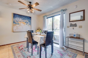 A dining area with a table set for four, a ceiling fan, a large abstract painting, and a view through a glass door. - 🌈Tranquil condo with cozy king beds🌈decaf/ regular coffee✨work from🏡✨fast wifi✨ (Las Vegas)