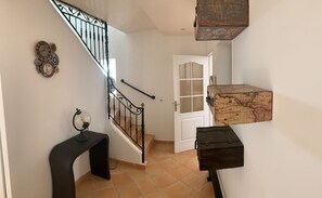 Staircase leads to a cozy space with a door, table, and shelf.