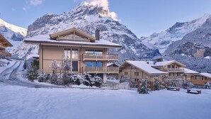 Un bâtiment de style chalet, doté d’un balcon et entouré de montagnes enneigées.