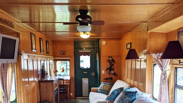 A cozy cabin interior with a bed, a small desk, and a television. - Grape Escape at Olympic Railway Inn - Pet Friendly (Sequim)