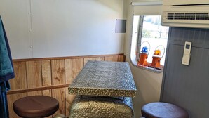 A compact kitchen with a wooden countertop, two stools, a vintage radio, and a window with a view. - Steampunk Train at Olympic Railway Inn - Pet Friendly (Sequim)