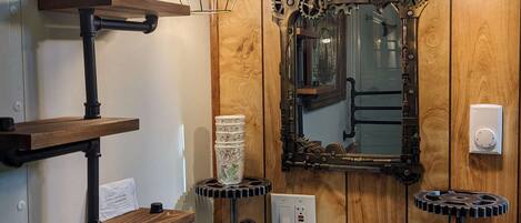 Une salle de bain avec un mur recouvert de panneaux en bois, un lavabo blanc, un miroir orné d’un motif en forme d’engrenage et deux appliques murales.
