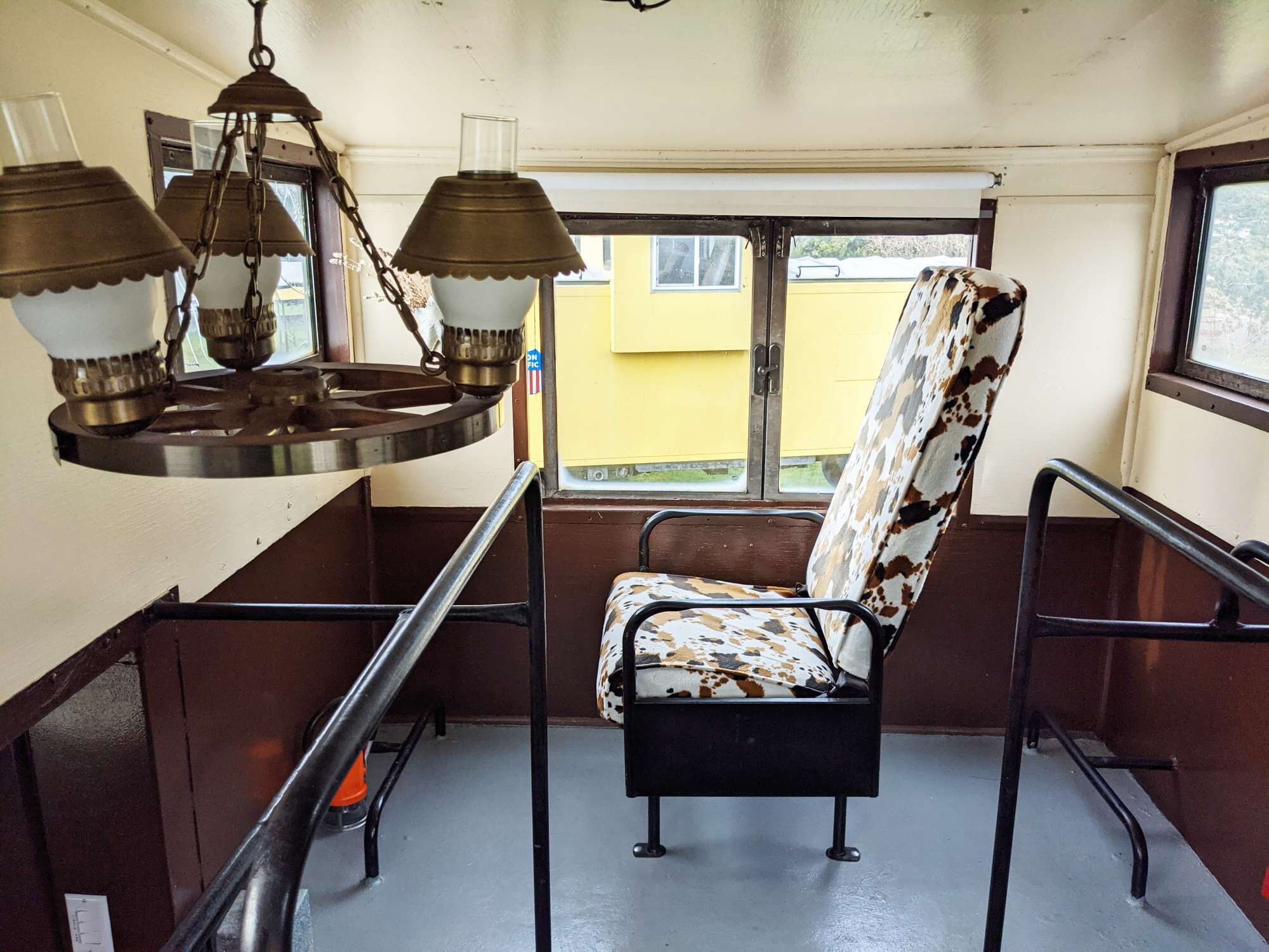 L'intérieur d'un wagon de train d'époque, avec un banc en métal, des barres d'appui en métal et un luminaire suspendu.