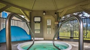 Une piscine extérieure couverte, équipée de deux échelles en métal, d’une porte sur laquelle sont affichés des panneaux et qui offre une vue sur une zone herbeuse.