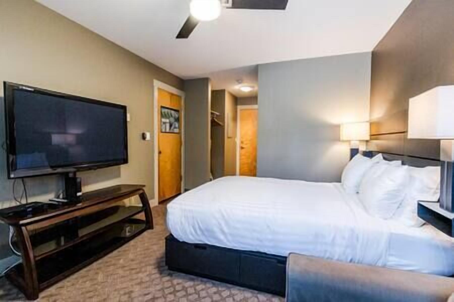 A hotel room with a bed, a television, and a desk.