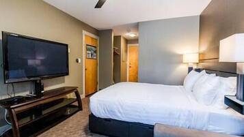 A hotel room with a bed, a television, and a desk.