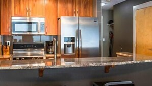 Une cuisine moderne avec des meubles en bois, des appareils en acier inoxydable et un plan de travail en marbre.