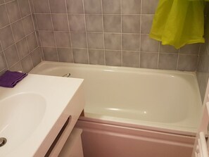 Ett badrum med ett vitt badkar, ett handfat och en toalett.