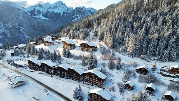 A snow-covered mountain resort with multiple chalet-style lodges, a ski slope, and dense forested areas. - 2 rooms + cabin with balcony and equipped kitchenette (Le Biot)