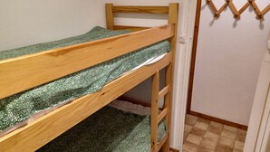 A bunk bed with green patterned bedding in a room with a tiled floor and a wooden wall decoration. - 2 rooms + cabin with balcony and equipped kitchenette (Le Biot)