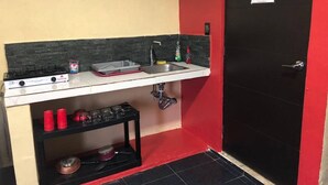 A compact kitchenette with a gas stove, sink, and storage shelves. - Super Cheap Loft Style Apartment in Merida Wifi Smartv (Mérida)