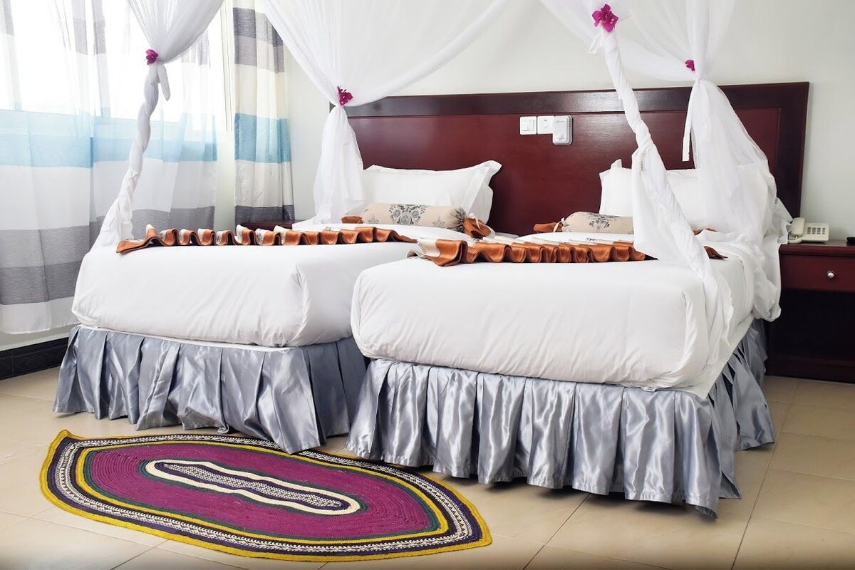 Un lit double à baldaquin, une table de chevet, un téléphone et un tapis à motifs.