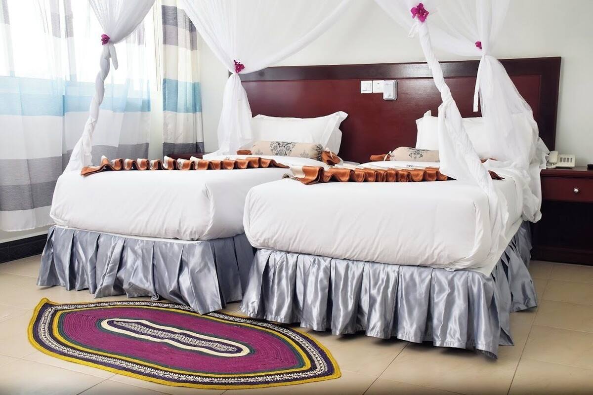 A double bed with a canopy, a bedside table, a phone, and a patterned rug.