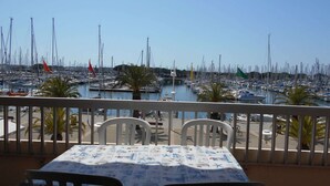 Un balcon avec une table et des chaises donnant sur une marina où sont amarrés de nombreux bateaux.