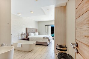A modern bedroom with a large bed, a bathtub, and a view of the outdoors. - Three Bedroom Apartment - De Waterkant (Cape Town)