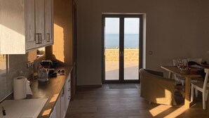 A modern kitchen with wooden cabinets and a view of the beach through a glass door. - Luxury Villa With Private Pool Kika Residences (West Mani)
