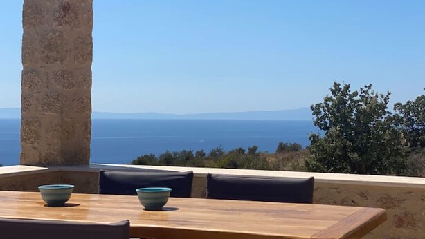 A wooden table with two bowls, a stone pillar, and a view of the sea and distant mountains. - Luxury Villa With Private Pool Kika Residences (West Mani)