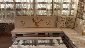 Un coin salon accueillant avec un banc rembourré et des coussins, une table basse en verre et un mur en pierre rustique.