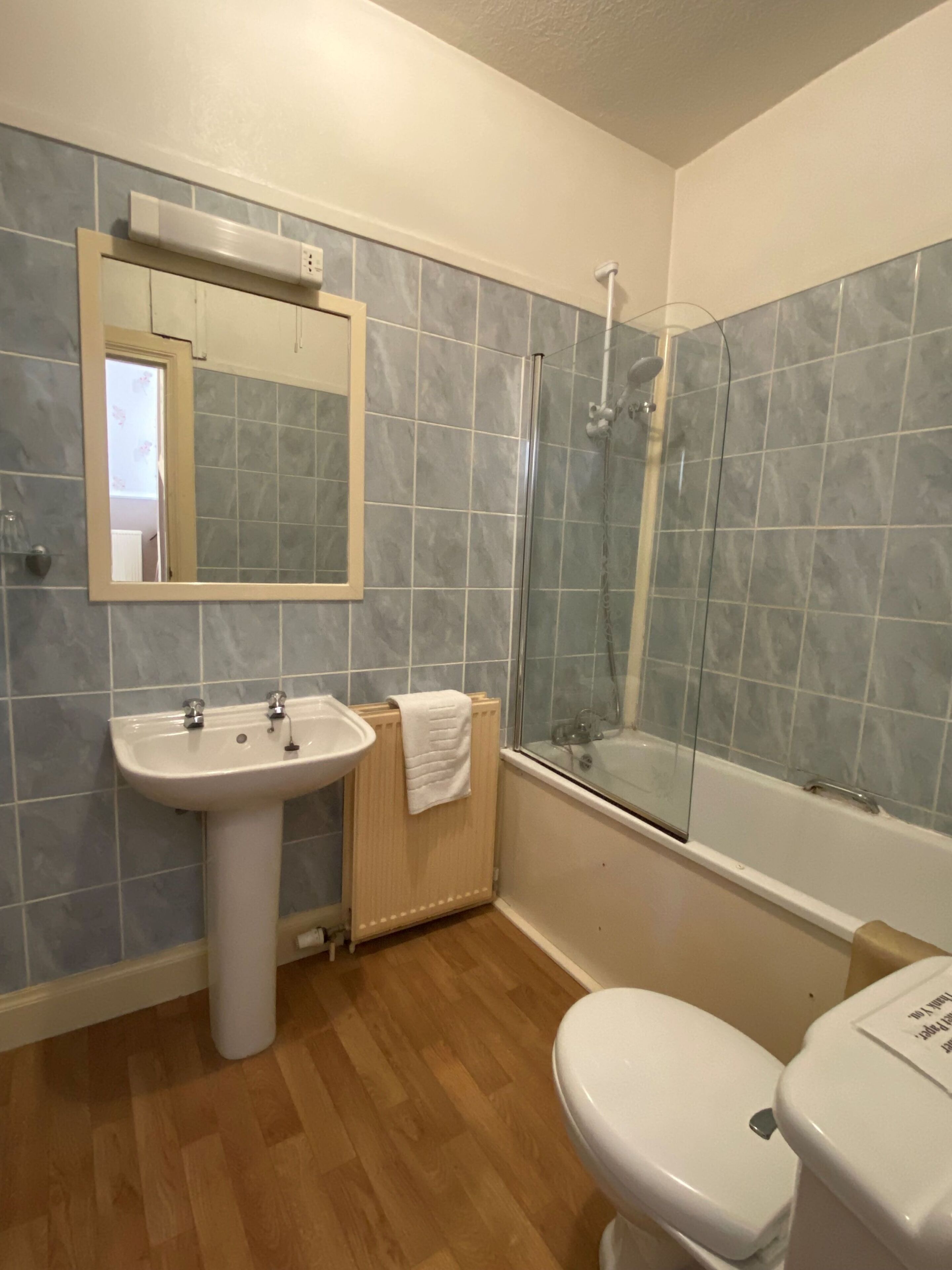 A bathroom with a sink, mirror, toilet, and shower.