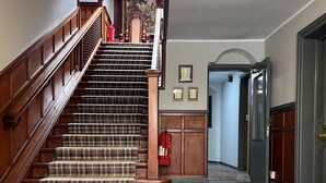 A staircase with a checkered carpet, wooden handrails, and a fire extinguisher. - The Kings Arms Hotel (Lockerbie)