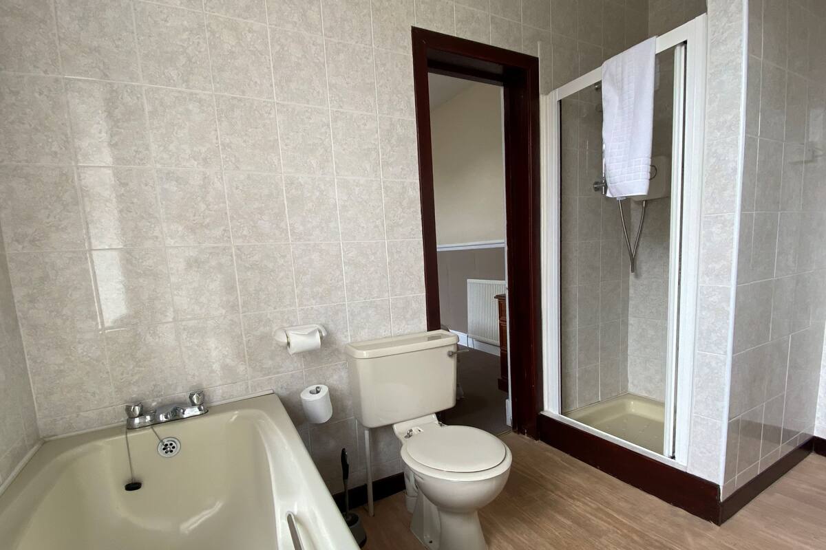 A bathroom with a bathtub, toilet, and walk-in shower.