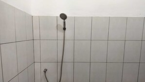 Eine Dusche mit Handbrause und flexiblen Schlauch, an einer gefliesten Wand befestigt.