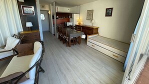 A compact living space with a dining area, a sofa, a small bed, and a kitchenette.