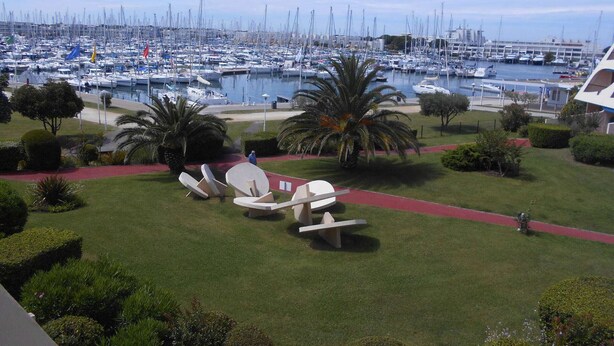A marina with numerous boats docked, surrounded by well-maintained greenery and palm trees.