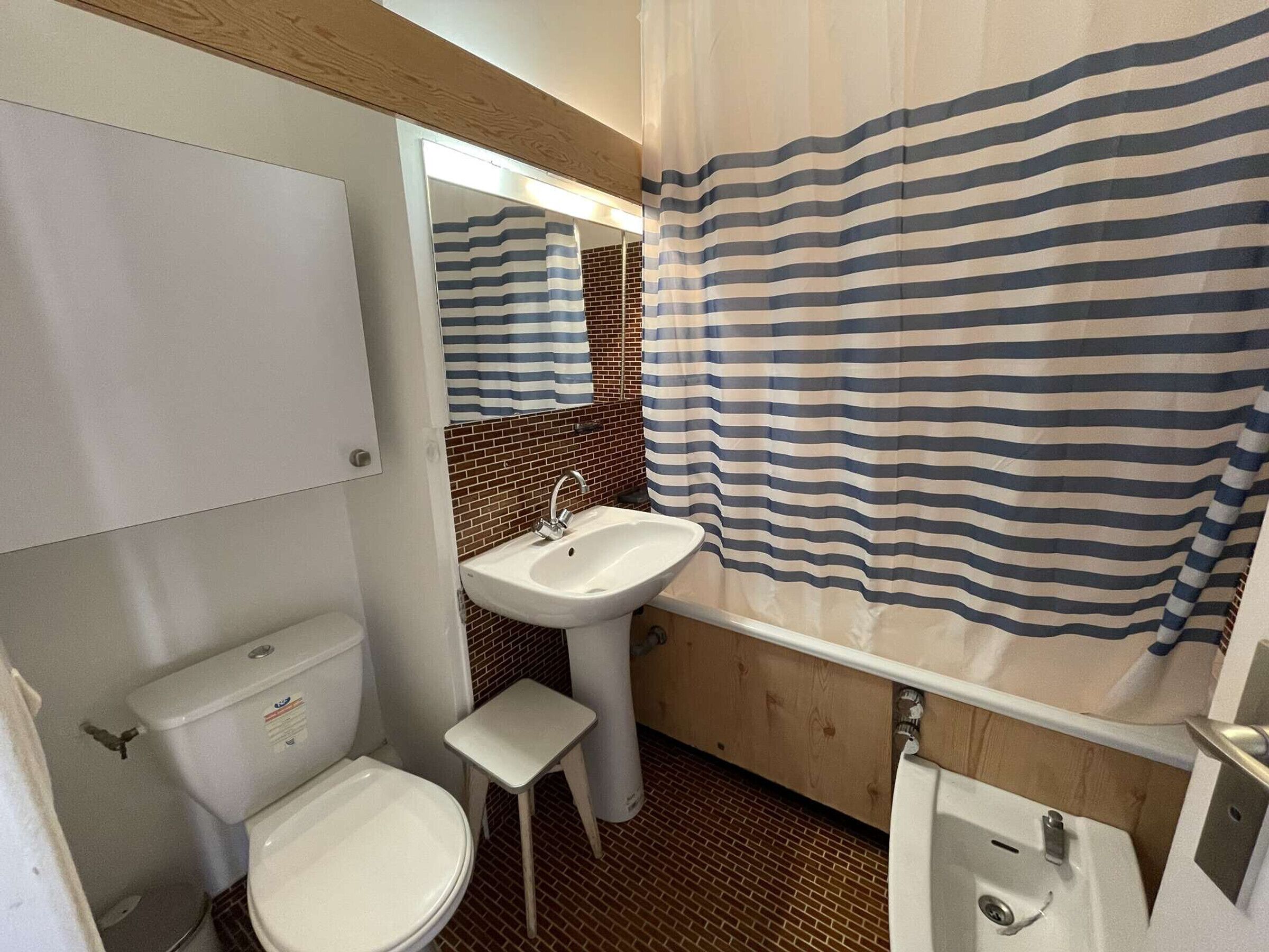 A compact bathroom with a toilet, sink, and shower area.