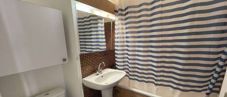 A compact bathroom with a toilet, sink, and shower area.