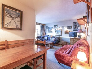 Relax in this inviting living room with a comfortable sofa, dining table, and TV.