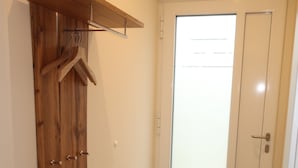 Un corridoio con un armadio in legno, un appendiabiti e una porta con pannello in vetro satinato.