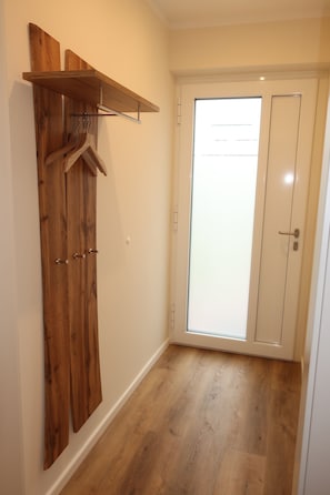 Ein Flur mit einem Holzschrank, einem Kleiderständer und einer Tür mit Milchglasfenster.