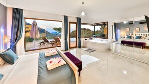 A modern hotel room with a large bed, a sitting area with a view, a separate bathroom, and a balcony with a view. - Villa Fiore (Antalya)