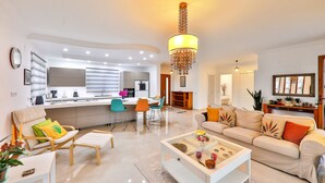 A modern living room with a sofa, coffee table, and a dining area with chairs. - Villa Fiore (Antalya)