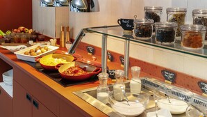 Un bufé con diversos alimentos, entre ellos frutas, yogur y un plato rojo con salsa.