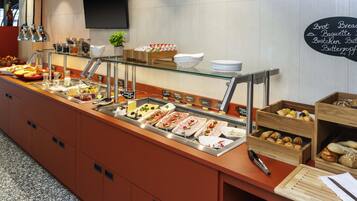 Un banco del buffet con diversi cibi e un menu su una lavagna.