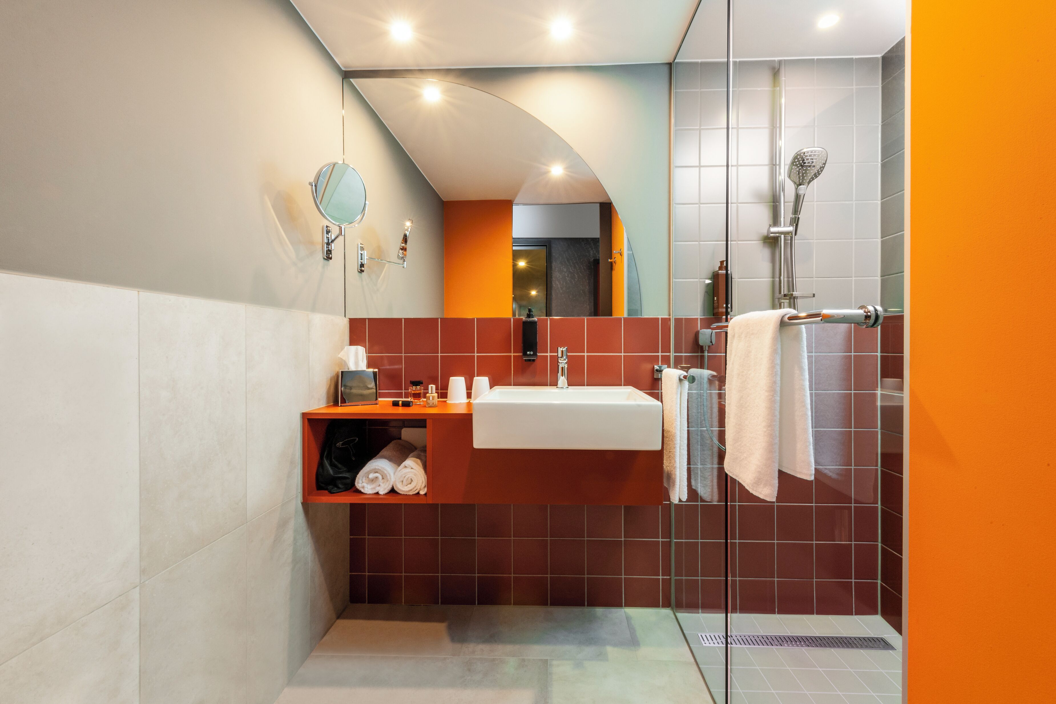 A modern bathroom with a sink, mirror, and shower.