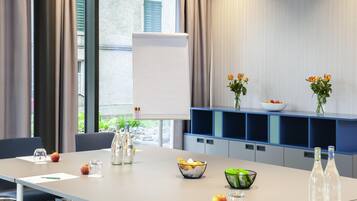 A conference room with a long table, chairs, a whiteboard, and a blue shelving unit with vases and bowls.