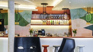 Un área de bar moderna con una barra, taburetes y una variedad de botellas y vasos.