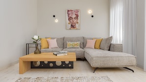 Uma sala de estar moderna com um sofá seccional, uma mesa de centro de madeira e um quadro na parede.