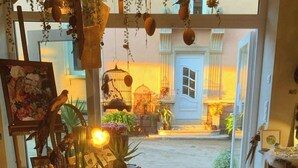 A cozy interior with a variety of decorative items, including a shoe display, hanging plants, and a birdcage. - Charming cottage in the countryside near Strasbourg (Fessenheim-le-Bas)