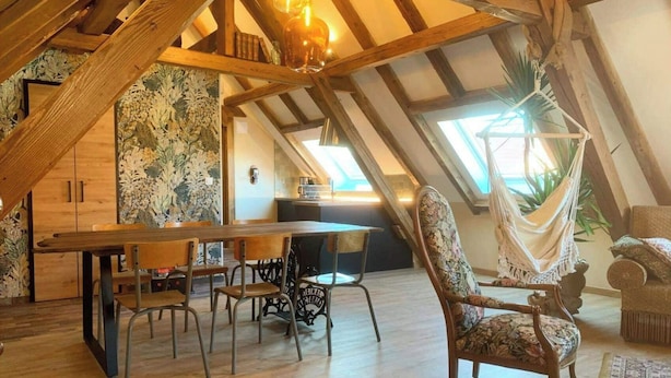 A cozy attic room with a wooden dining table, chairs, and a hammock. - Charming cottage in the countryside near Strasbourg (Fessenheim-le-Bas)
