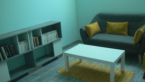 Un salon avec un canapé gris, une table basse blanche et une bibliothèque remplie de livres.