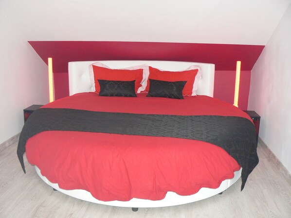 A bed with a red and black bedspread, two black pillows, and a white headboard.